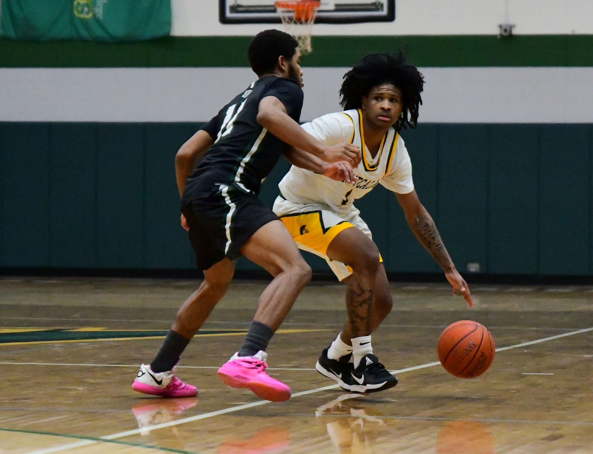 MCC men's basketball player defending the ball from an oppossing player.