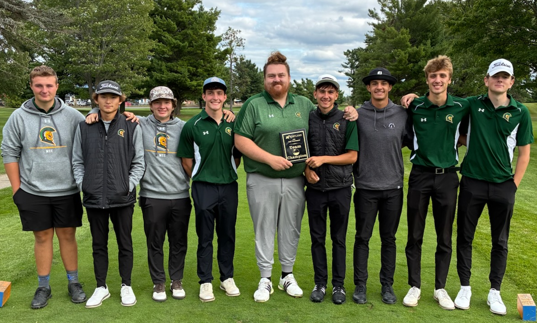 Team photo of the 25-26 men's golf team standing on a golf course holding up a plaque.