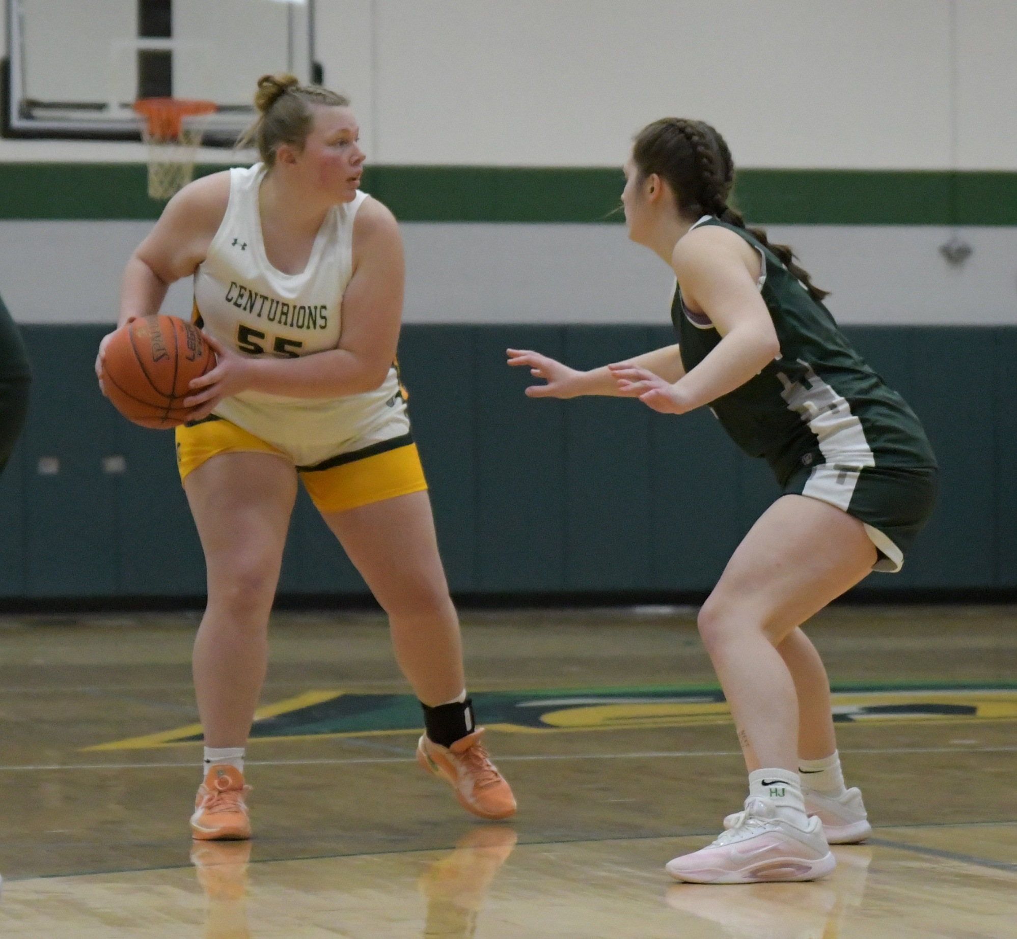 Women's basketball player looking to pass the ball around an opposing player.
