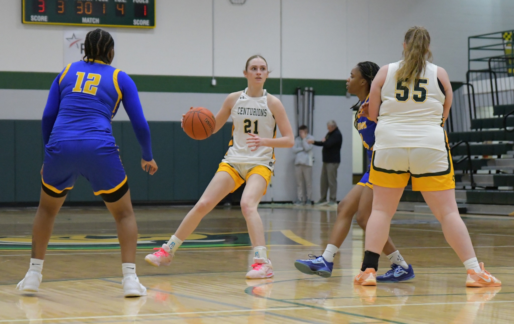 MCC women's basketball player Emma Rehkopf dribbling the ball on the home court during a game with opposing players and teammates surronding her.