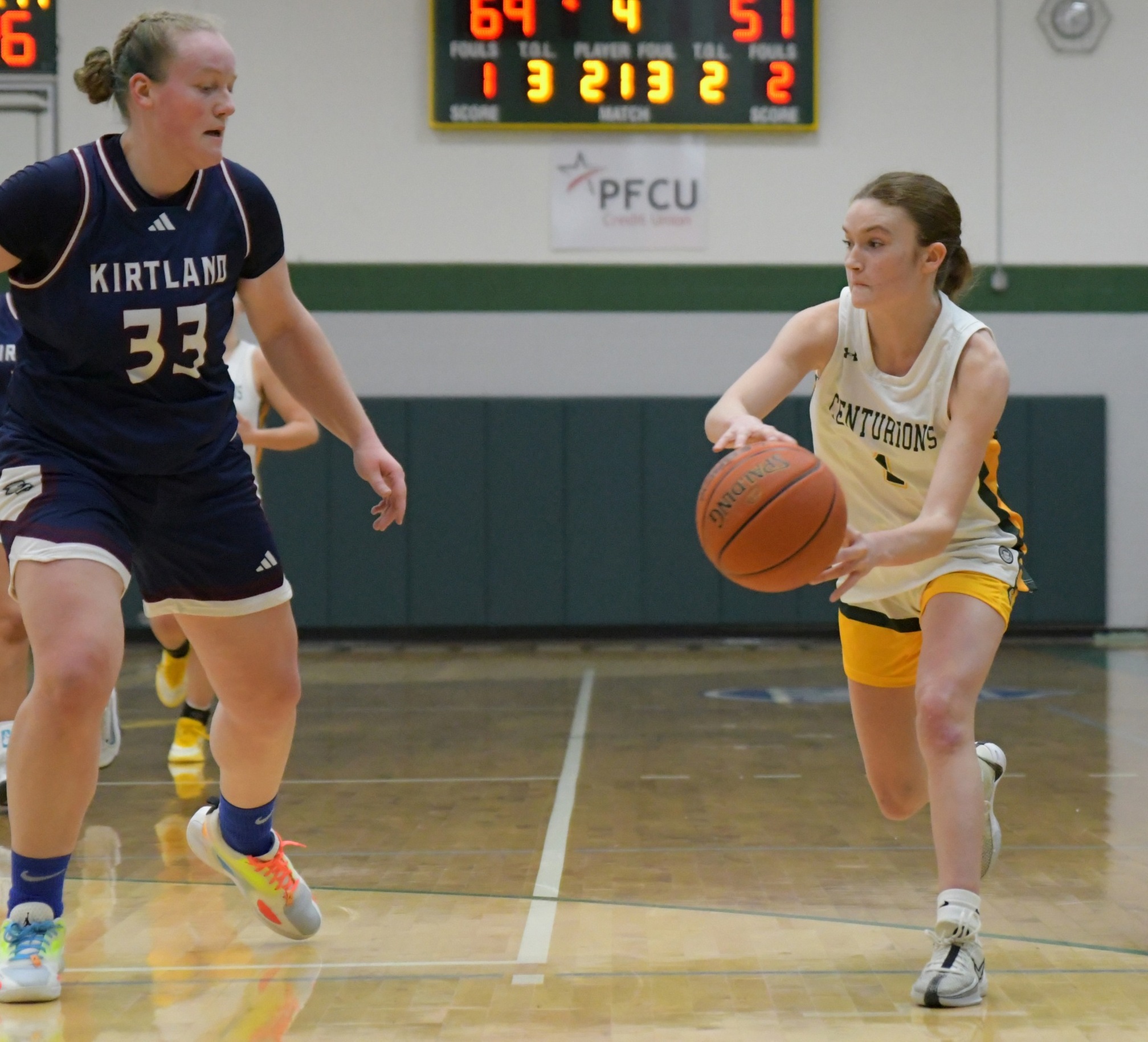 MCC women's basketball player preparing to pass the ball on the court around an opposing team member.