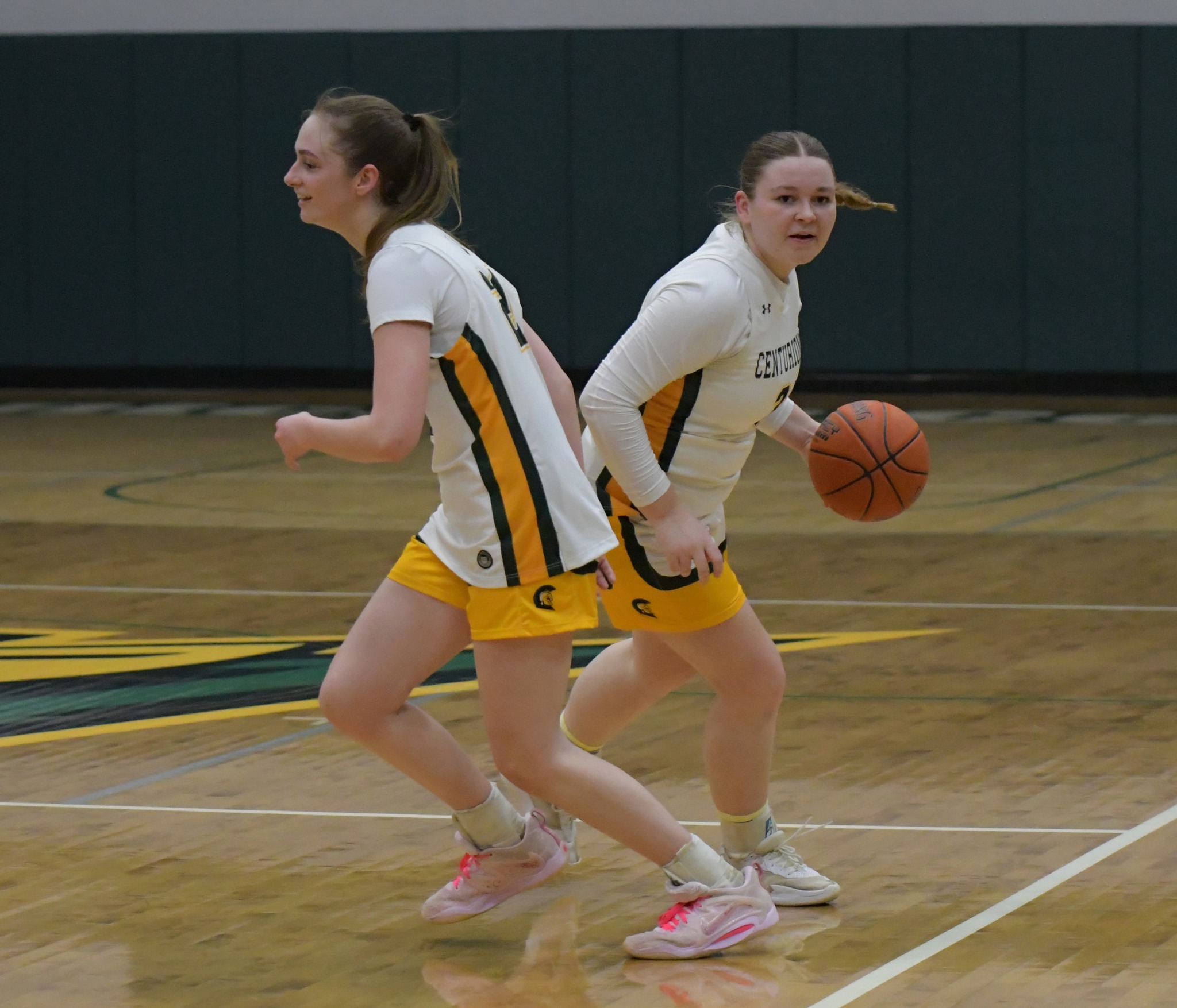 Two MCC women's basketball players running on the court during a game.