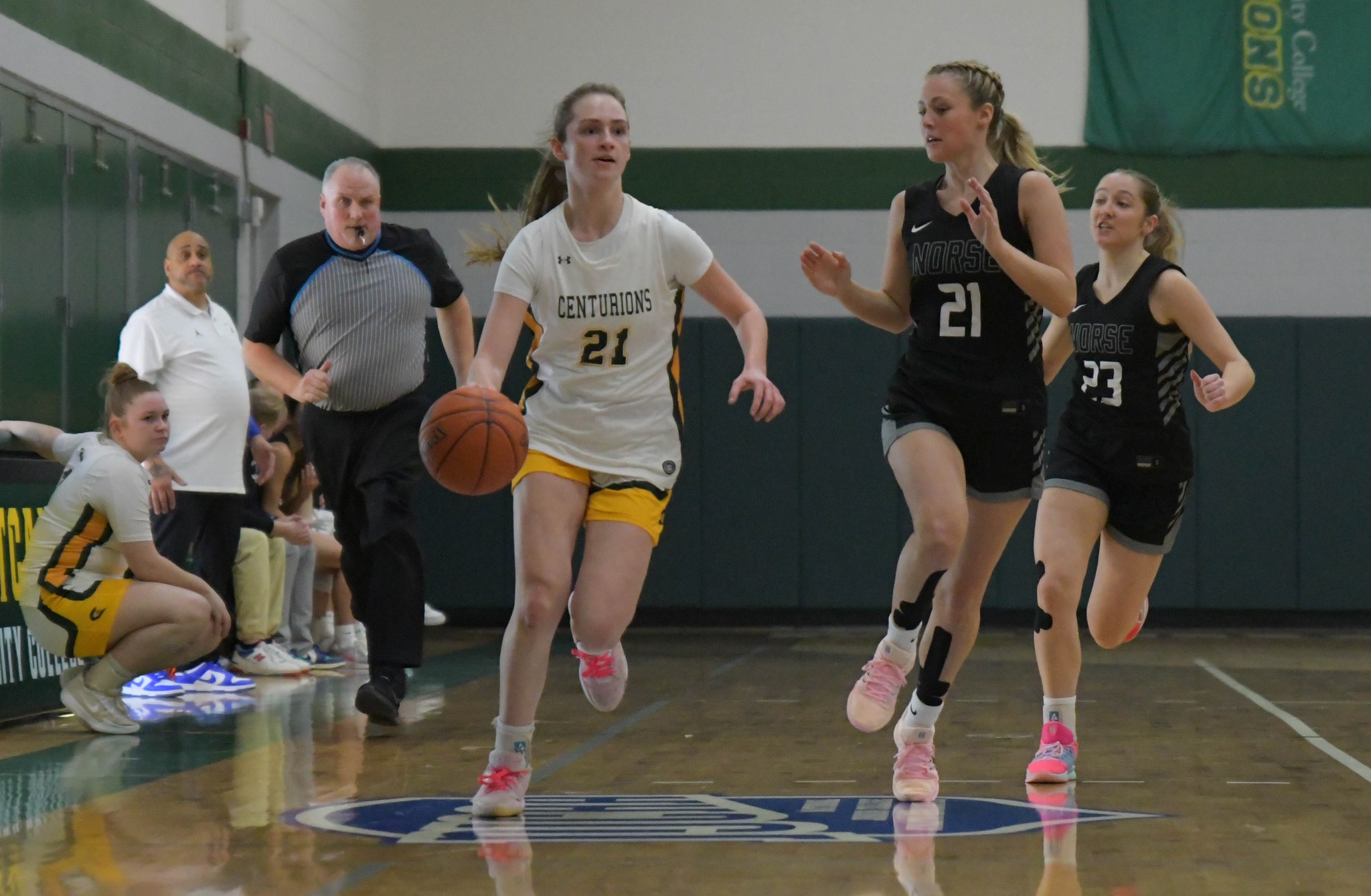 MCC women's basketball player dribbles the ball down the court with an oppossing player next to her.